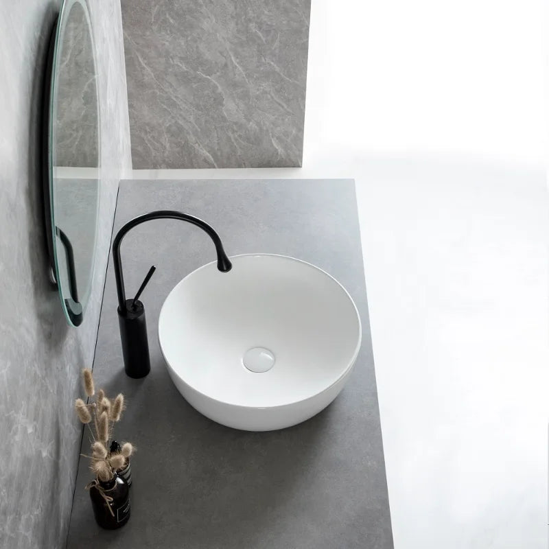 White round ceramic bathroom vessel sink with silver faucet and drain, perfect for modern countertop or vanity installations.