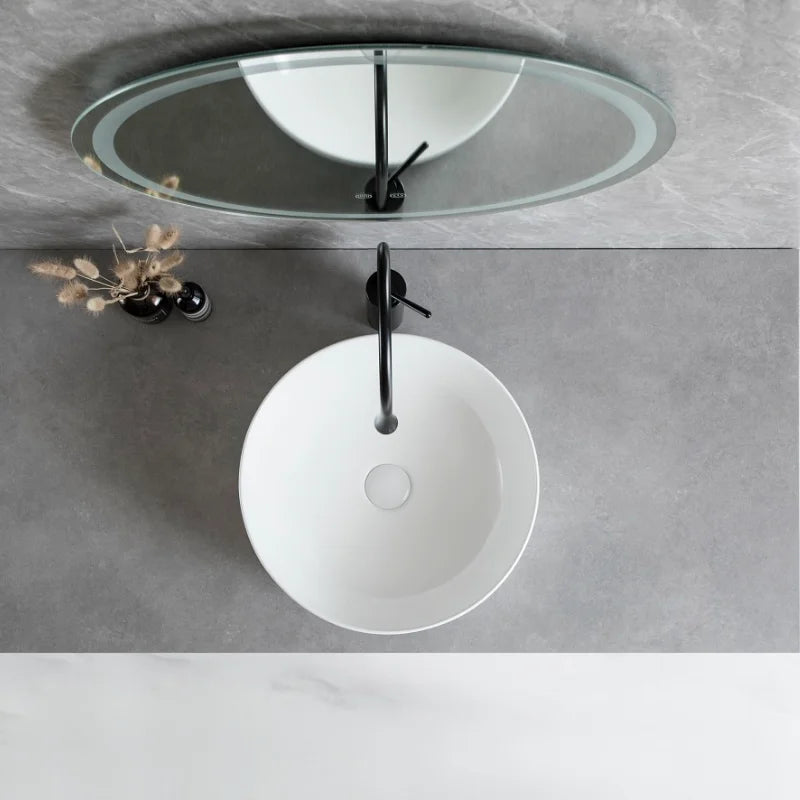 White round ceramic bathroom vessel sink with silver faucet and drain, perfect for modern countertop or vanity installations.